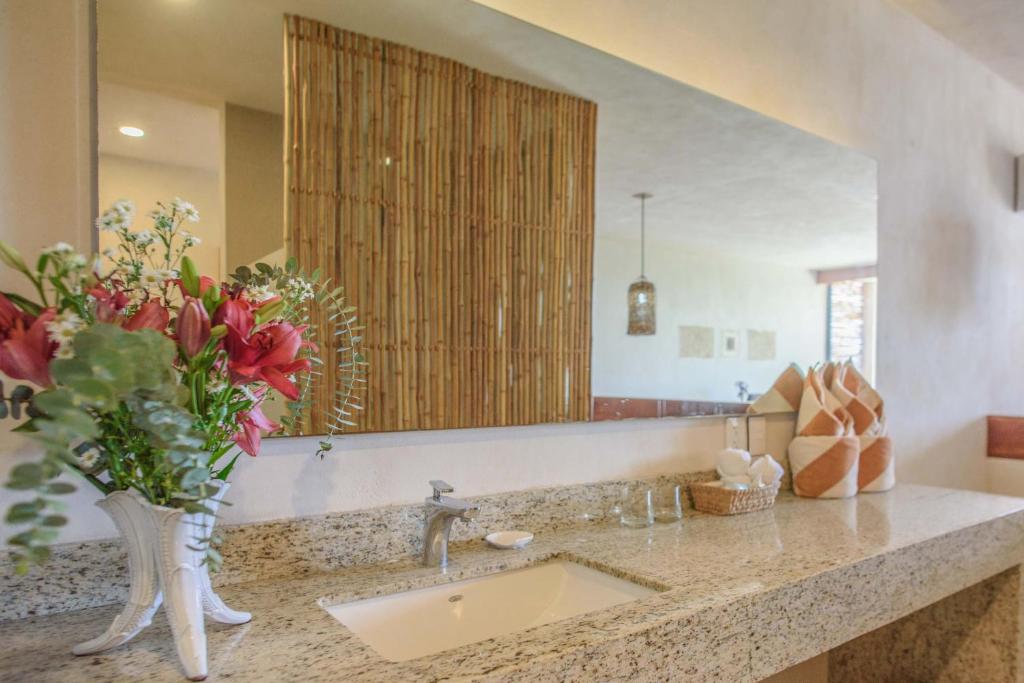 a bathroom with a sink and a vase with flowers at Los Arrecifes in Tulum