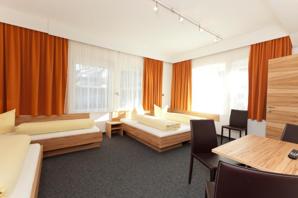 a room with two beds and a table and chairs at Hotel Garni Gletschertor in Ötztal-Bahnhof