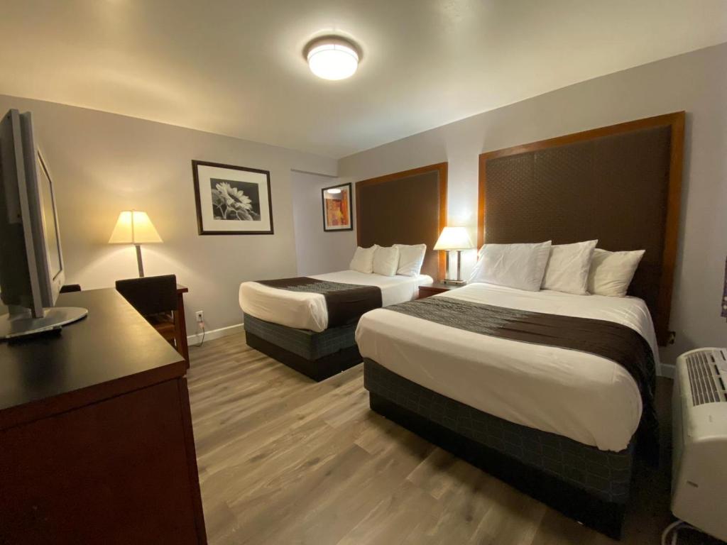 um quarto de hotel com duas camas e uma televisão de ecrã plano em Colonial Motel em Santa Maria