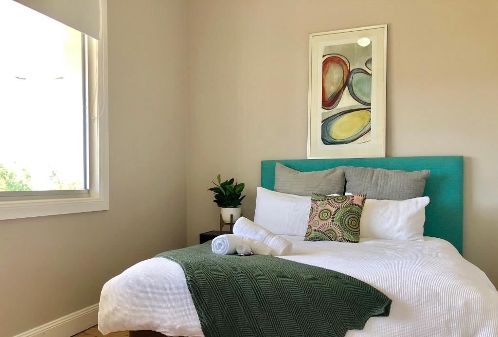 a bedroom with a large bed with a green headboard at Renovated Little Cottage Aberdare Hunter Valley in Aberdare