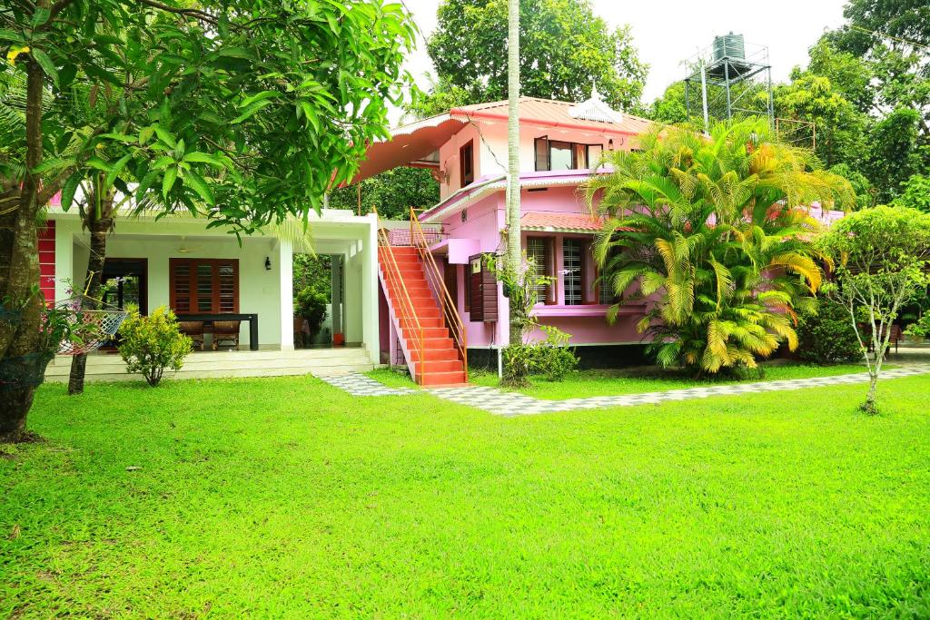 una casa rosa con césped delante en Marari Nest Beach Homestay, en Mararikulam