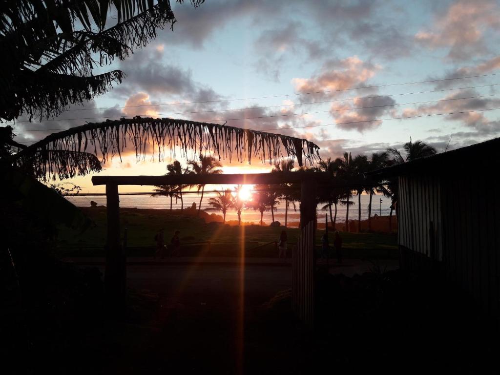 a sunset with the sun shining through a roof at Hostal Vieroto in Hanga Roa