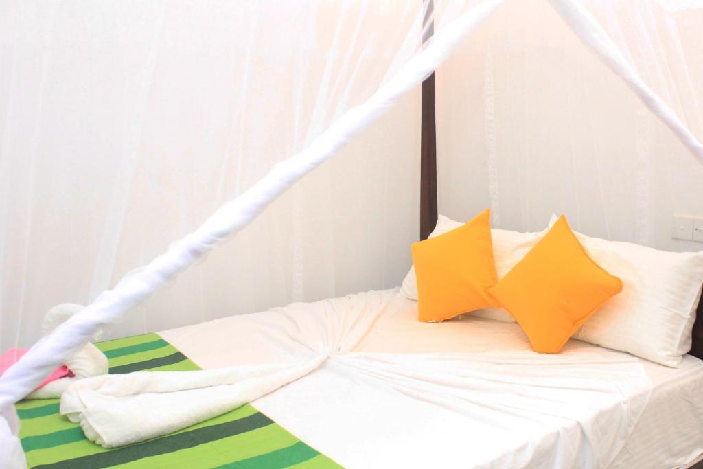 a bed with white sheets and yellow pillows at Hotel BEJEWELLED Sigiriya in Sigiriya