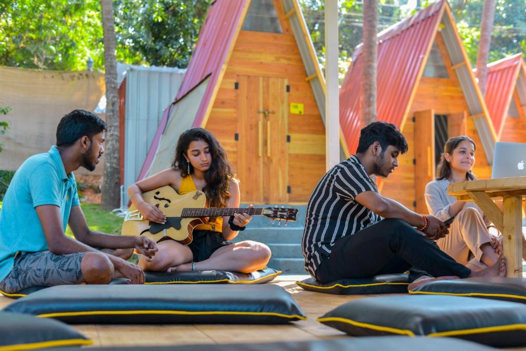 a group of people sitting on the ground playing guitar at The Hosteller Goa, Anjuna in Anjuna