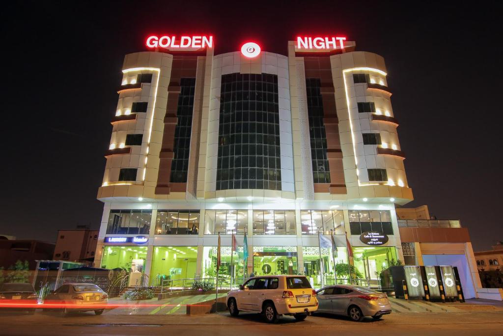 Golden Night Hotel في نجران: مبنى فيه سيارات تقف امامه