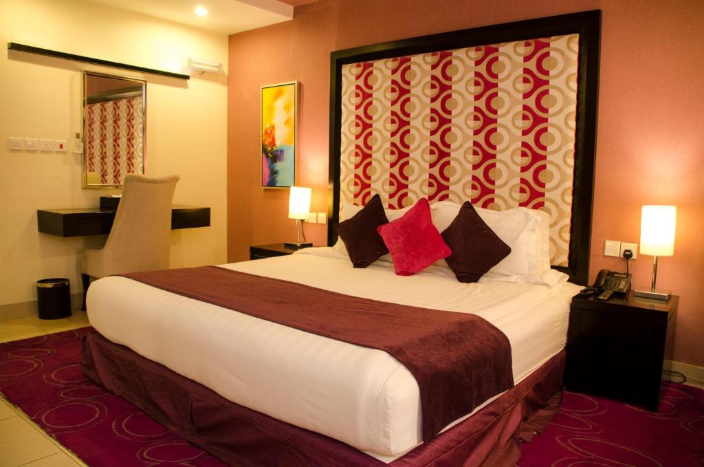 a hotel room with a large bed with red pillows at Swiss Spirit Hotel & Suites Taif in Taif