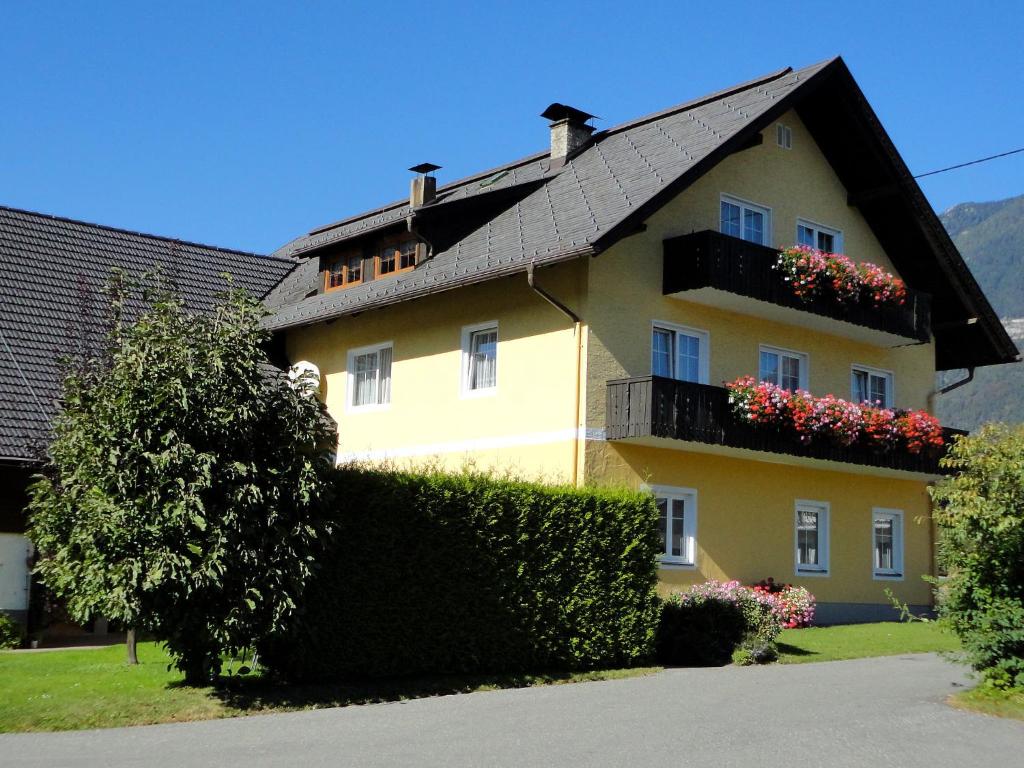 a yellow house with a black roof and flower boxes at Ferienhaus Ball - Kometterhof in Hermagor