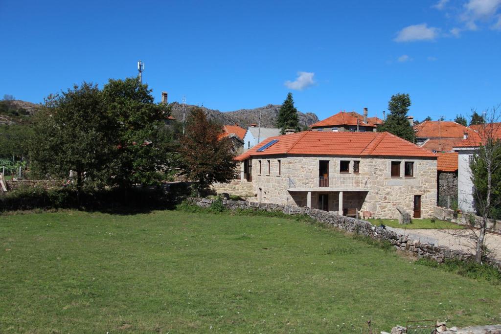 una casa de piedra con techo rojo en un campo en Casa Fonte Do Laboreiro, en Castro Laboreiro