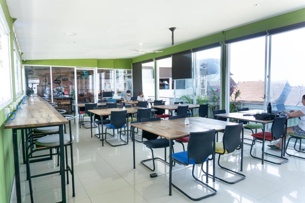 a restaurant with tables and chairs and windows at Matra Co Working & Co Living in Canggu