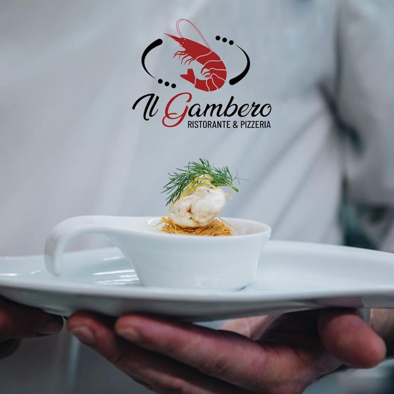a person holding a plate with a dish on it at Hotel Corallo in Francavilla al Mare