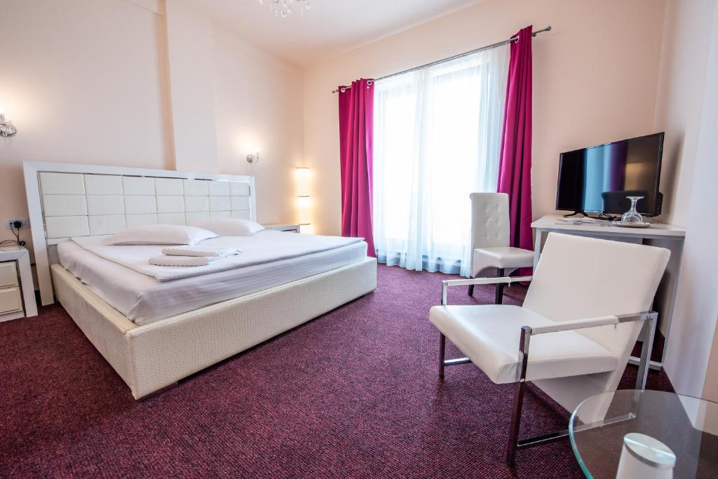 1 dormitorio con 1 cama, 1 silla y TV en Hotel Imperial Premium, en Timisoara