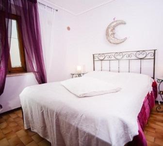 a bedroom with a white bed with purple curtains at B&B Monferrato La Casa Sui Tetti in Murisengo