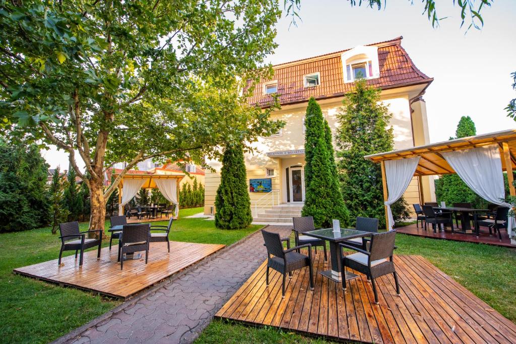 una terraza de madera con sillas y mesas en un patio en Hotel Imperial en Timisoara