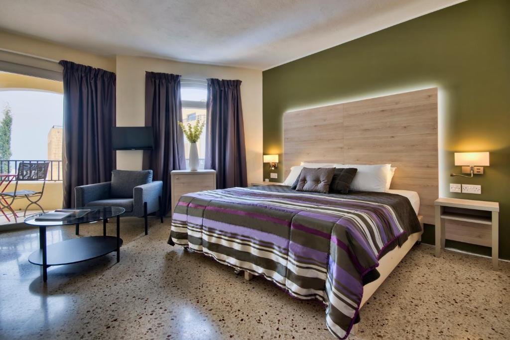 1 dormitorio con 1 cama grande y 1 silla en Il Palazzin Hotel en St Paul's Bay