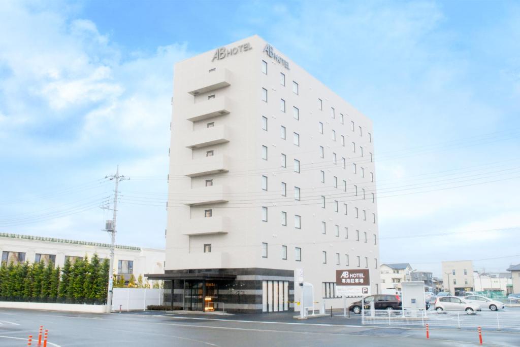 un grand bâtiment blanc au coin d'une rue dans l'établissement AB Hotel Isesaki, à Isesaki