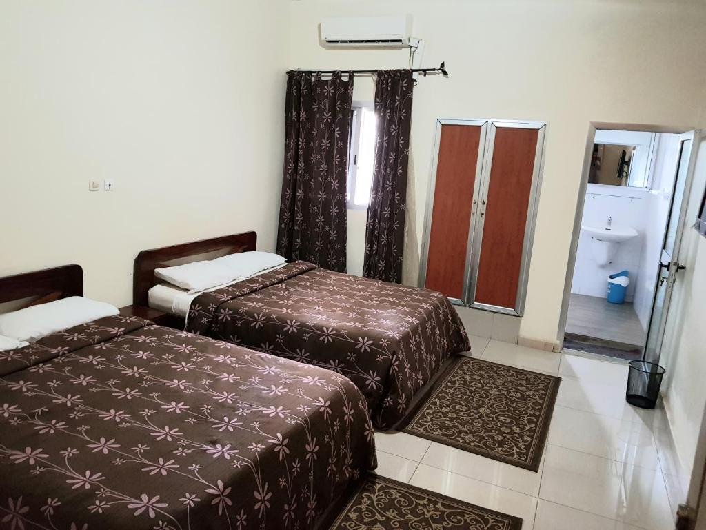 a hotel room with two beds and a mirror at Hotel du Golfe de Guinee in Conakry