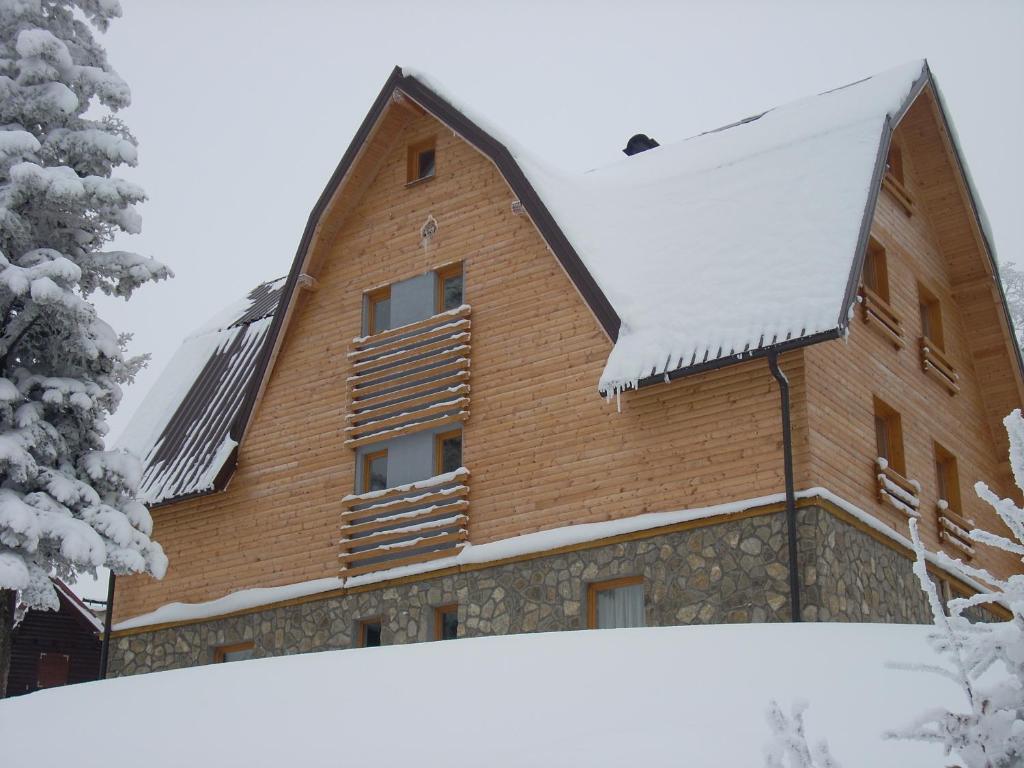 a wooden house with snow on the roof at Apartmani Marija in Jahorina