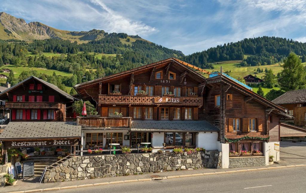 un grand bâtiment en bois sur le côté d'une rue dans l'établissement Hotel Restaurant Les Lilas, aux Diablerets