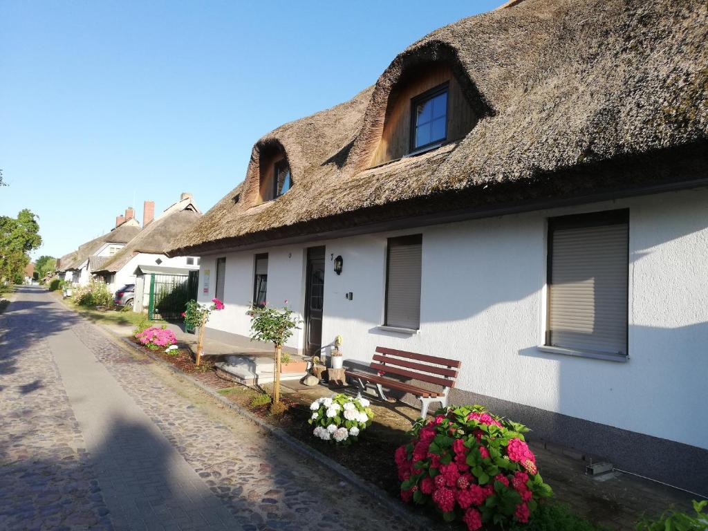 Lancken-Granitz的住宿－Haus - Meeresbrise，一座带茅草屋顶的建筑,上面有长凳和鲜花