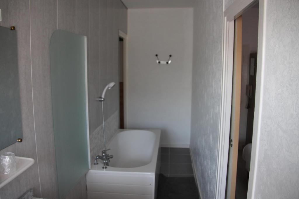 La salle de bains est pourvue d'une baignoire, d'un lavabo et d'une baignoire. dans l'établissement Hostellerie du Beffroy, à Besse-et-Saint-Anastaise