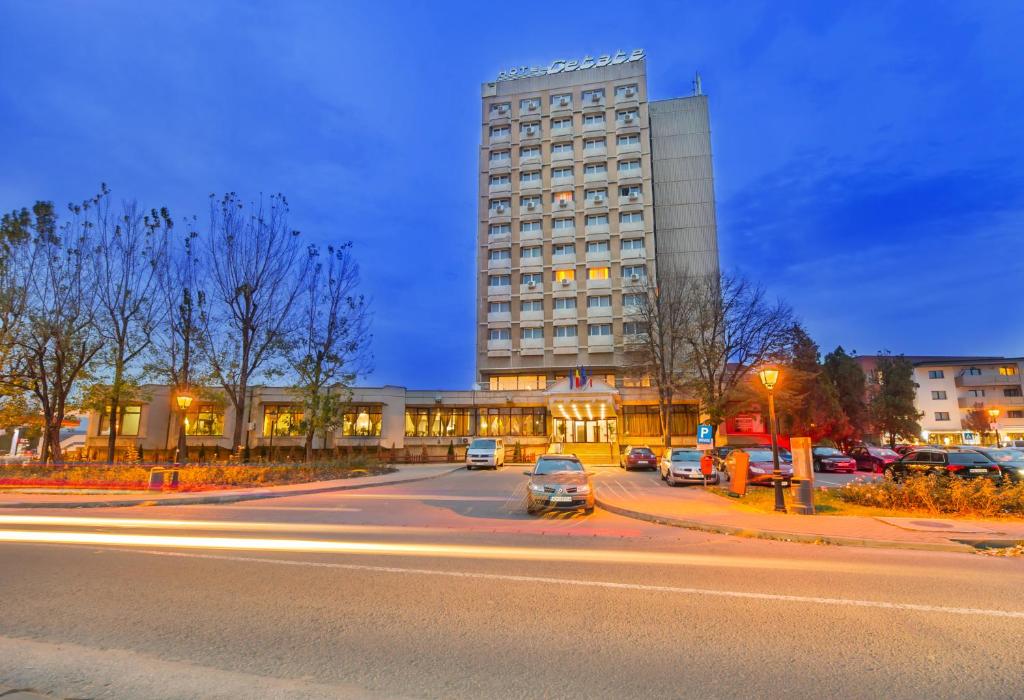 a tall building with cars parked in front of a street at Hotel Cetate in Alba Iulia