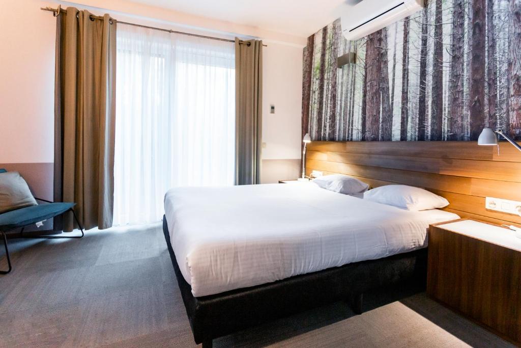 a bedroom with a large bed and a large window at Utopia Hotel - Art & Nature Hotel in Mons