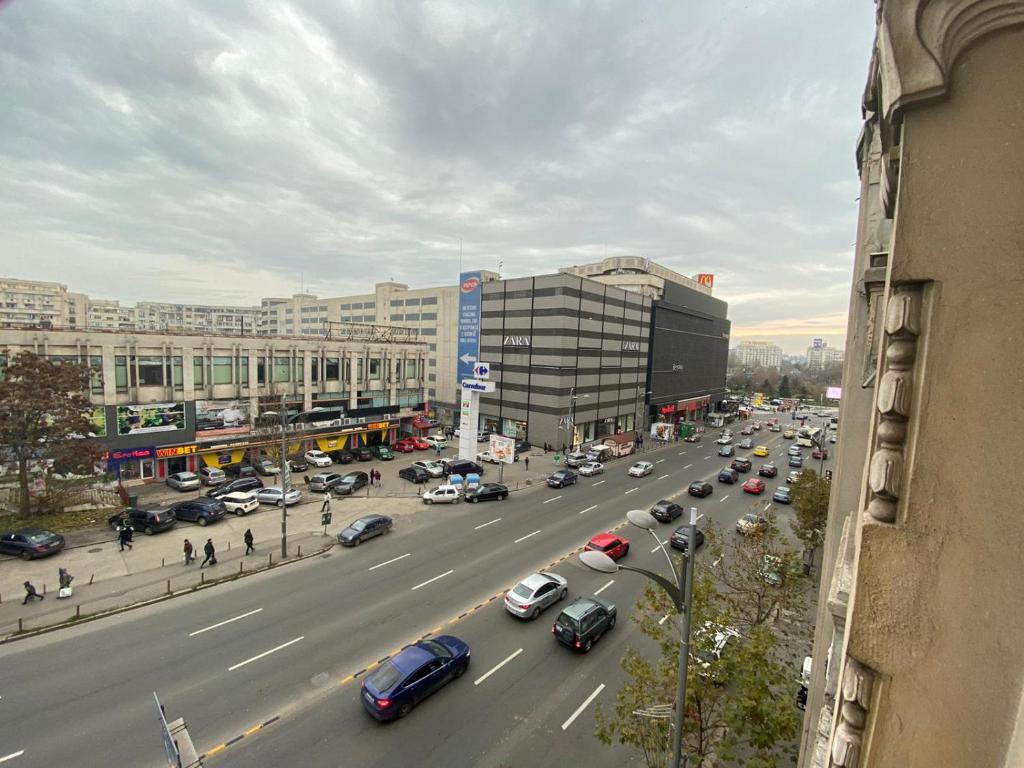 una concurrida calle de la ciudad llena de coches y edificios en Union Square SweetHome en Bucarest