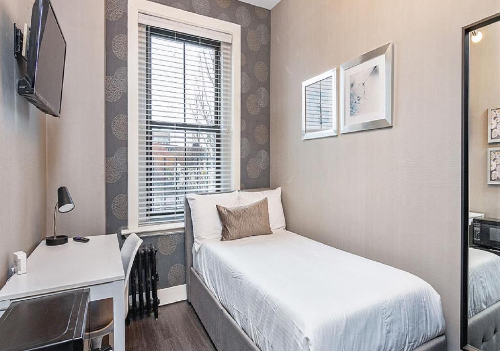 a bedroom with a bed and a desk and a window at Suites At 143 Arlington Street in Boston