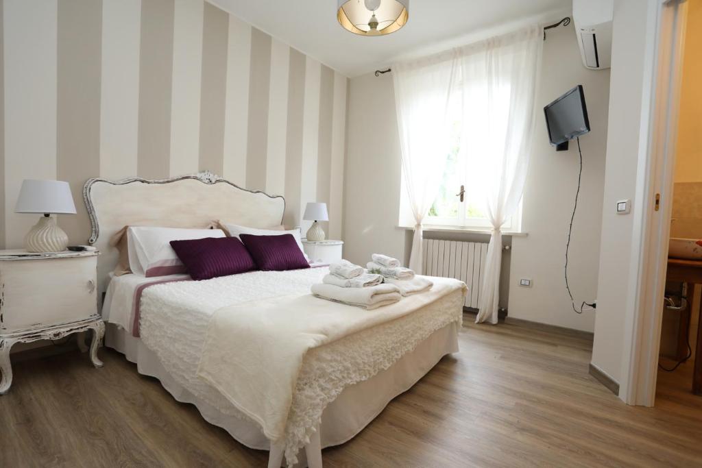 a bedroom with a white bed with purple pillows at Tra i Campi Di Papaveri in Medesano