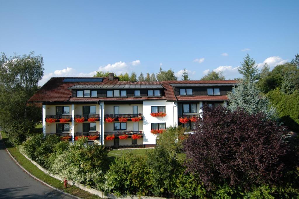 duży biały budynek z skrzyniami kwiatowymi na oknach w obiekcie Hotel Dreisonnenberg w mieście Neuschönau
