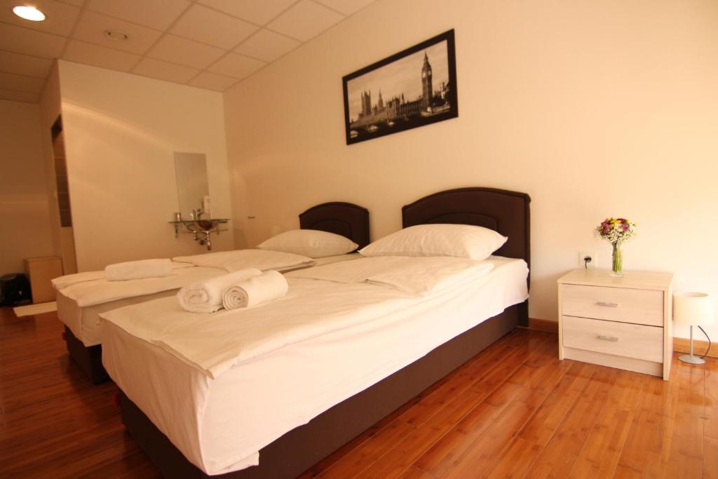 a bedroom with two beds with white sheets and towels at Rooms XXL in Zagreb