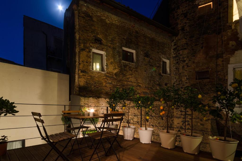 una mesa y sillas en un balcón por la noche en Pietranera Apartments, en Catania