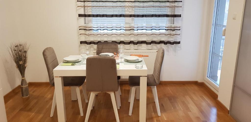 a dining room with a white table and chairs at Paris apartment -Free private parking in Novi Sad