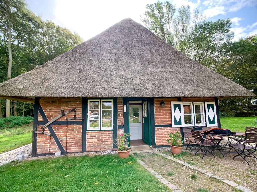 Reetdachkate في Neukirchen: منزل من الطوب صغير مع سقف من القش
