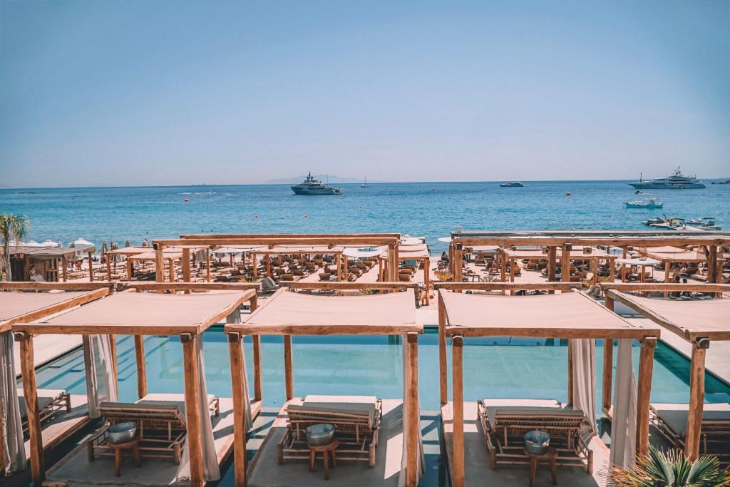 a beach with tables and chairs and the ocean at Branco Mykonos in Platis Gialos