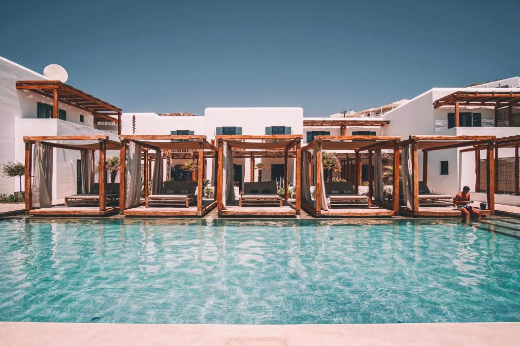 a man sitting on the edge of a pool at a resort at Branco Mykonos in Platis Gialos