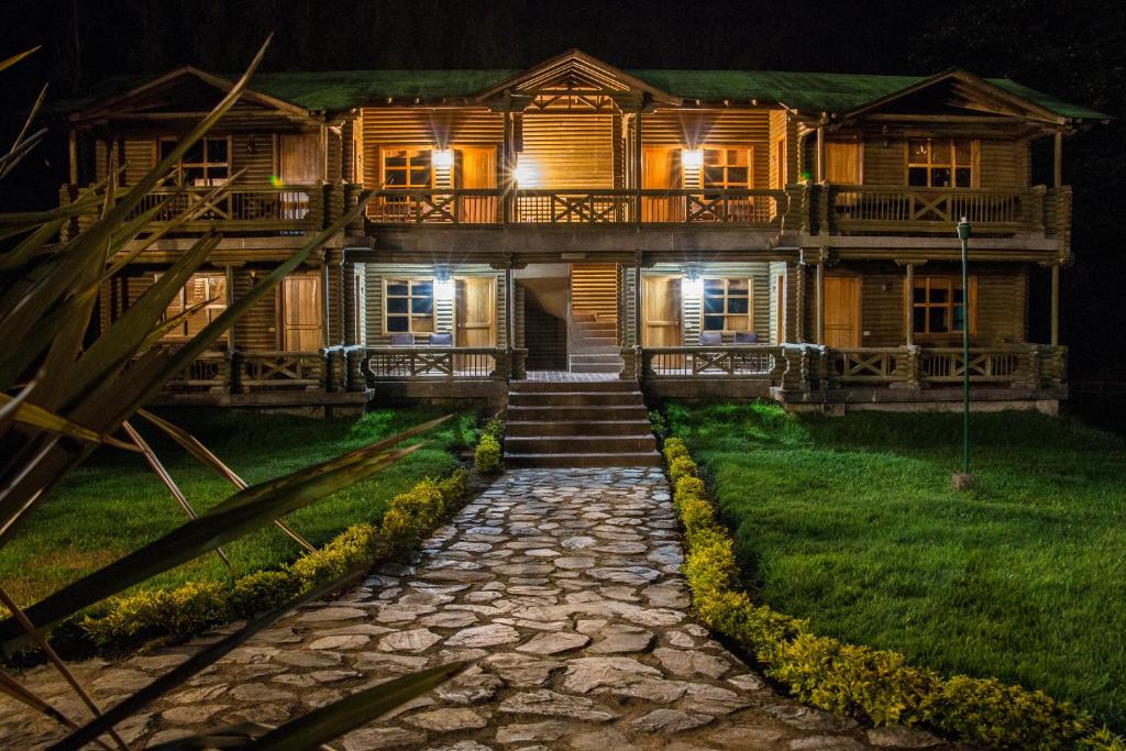 una casa de madera por la noche con un camino de piedra delante en HOTEL IGUAIMA, en Ibagué