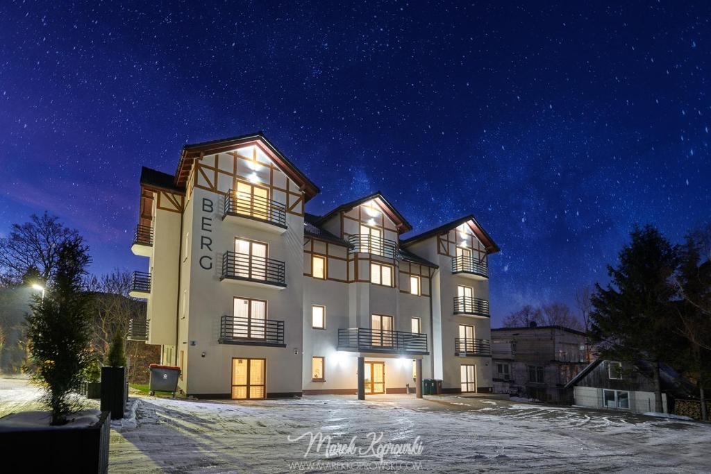 un bâtiment dans la neige la nuit dans l'établissement Apartamenty Berg Karpacz, à Karpacz