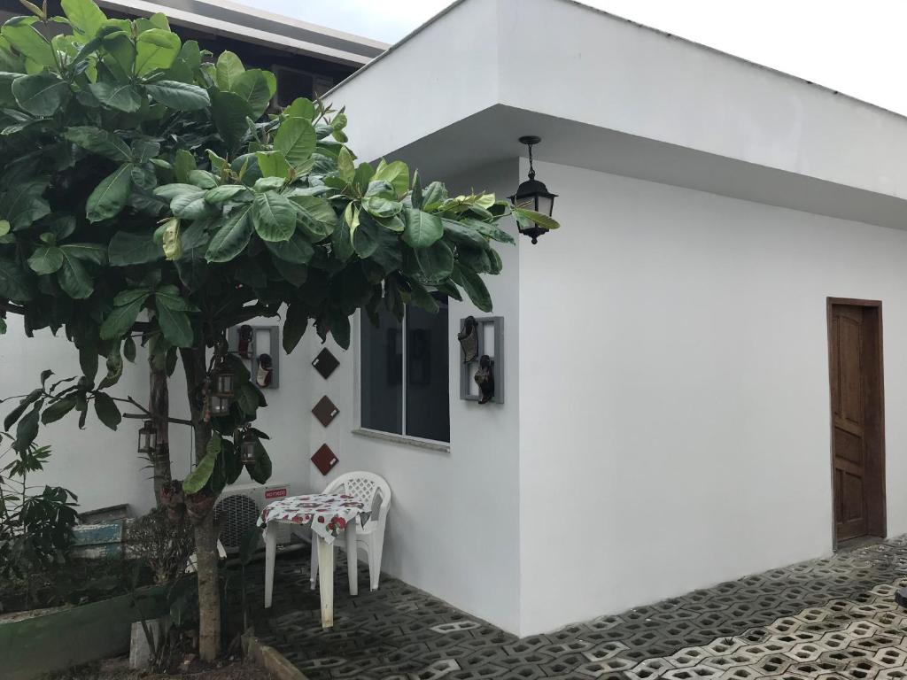 una casa blanca con dos sillas y un árbol en Cafofo Luxo Mariscal, en Bombinhas