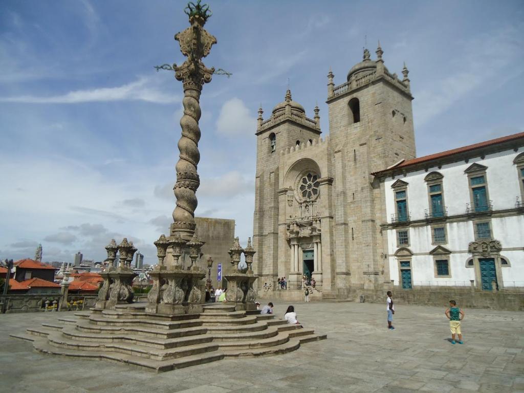 a statue in front of a building with a tower at Guest House Triunfo in Porto