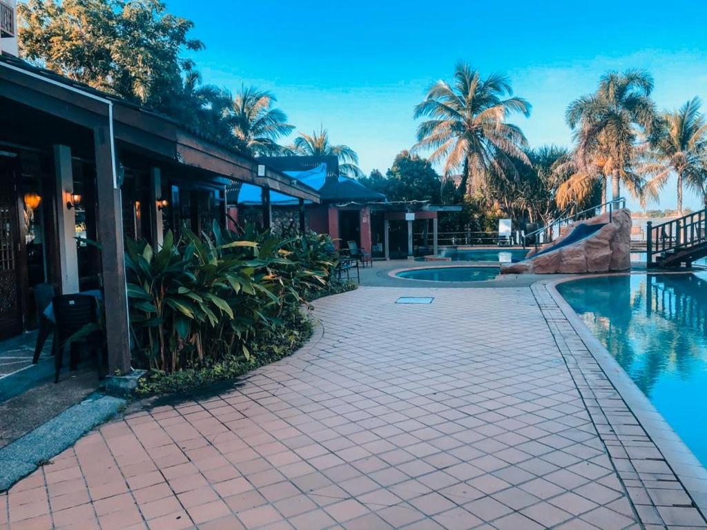 un complexe avec une piscine et des palmiers dans l'établissement LANGKAWI LAGOON RESORT OCEAN SUITE, à Pantai Cenang