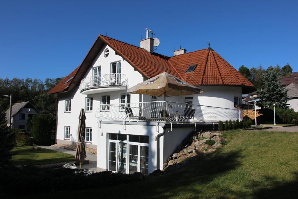 a white house with a balcony and an umbrella at Pension Najdek in Žďár nad Sázavou