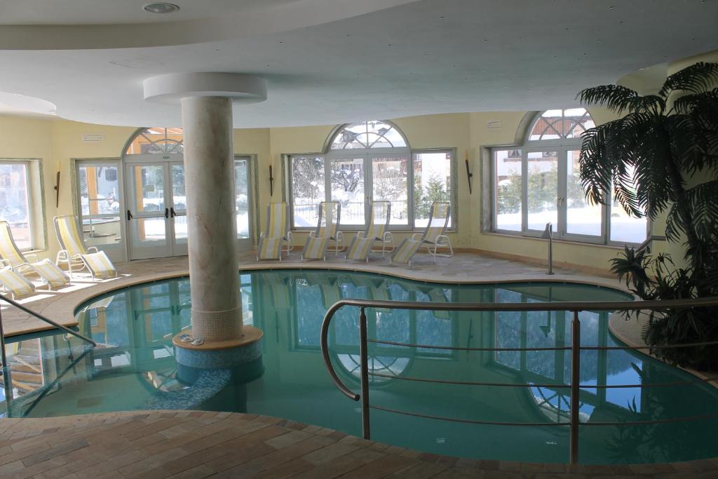a large swimming pool with chairs in a building at Hotel Canada in Pinzolo