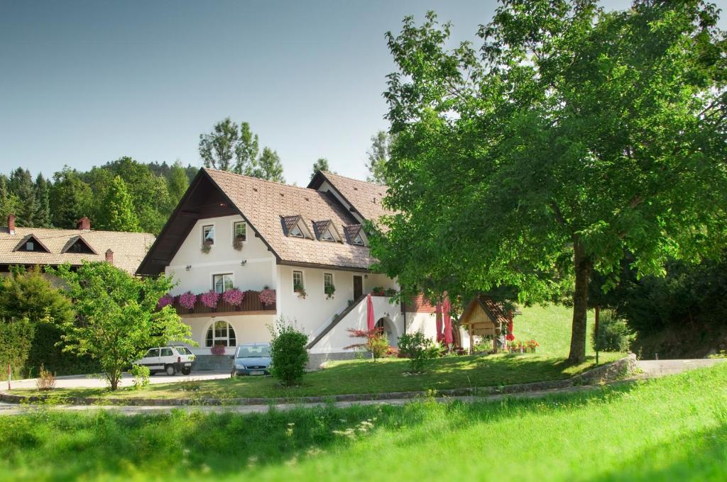 a large white house with a tree in the yard at B&B Na Kluk in Idrija