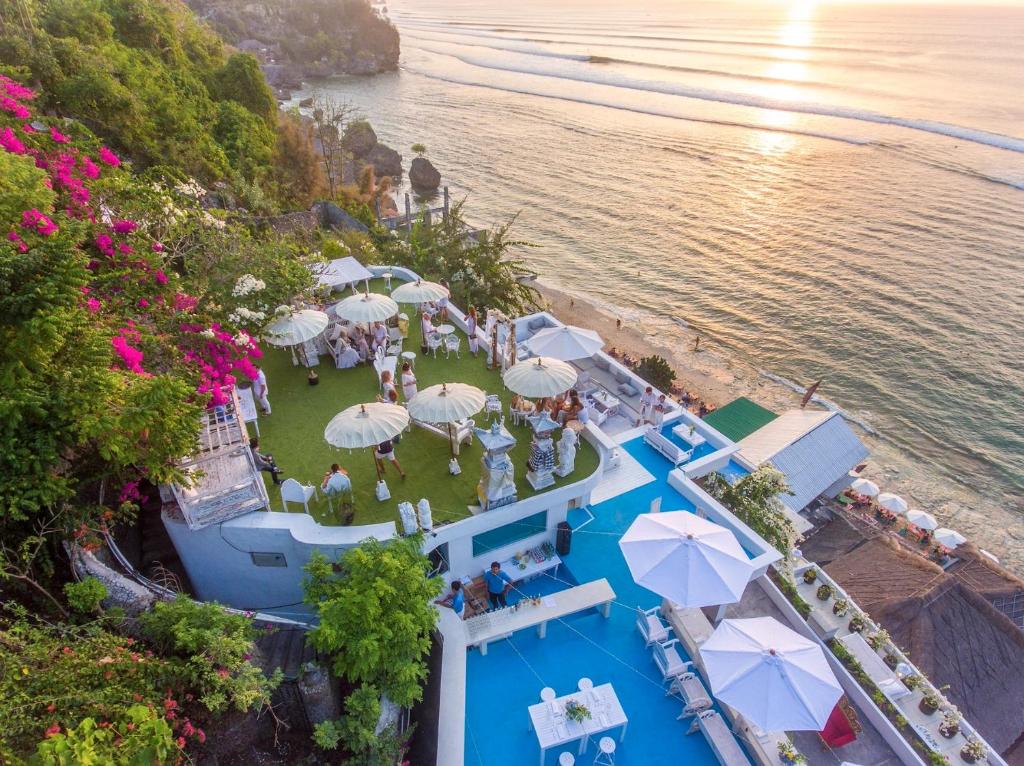 an overhead view of a pool with umbrellas and a beach at Morabito Art Cliff in Uluwatu