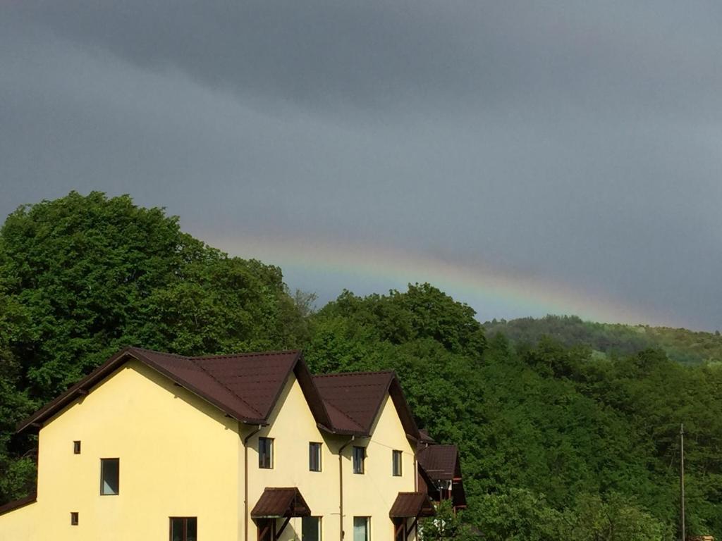 Biały dom z brązowym dachem przed górą w obiekcie Vila Chiojdu w mieście Buzau