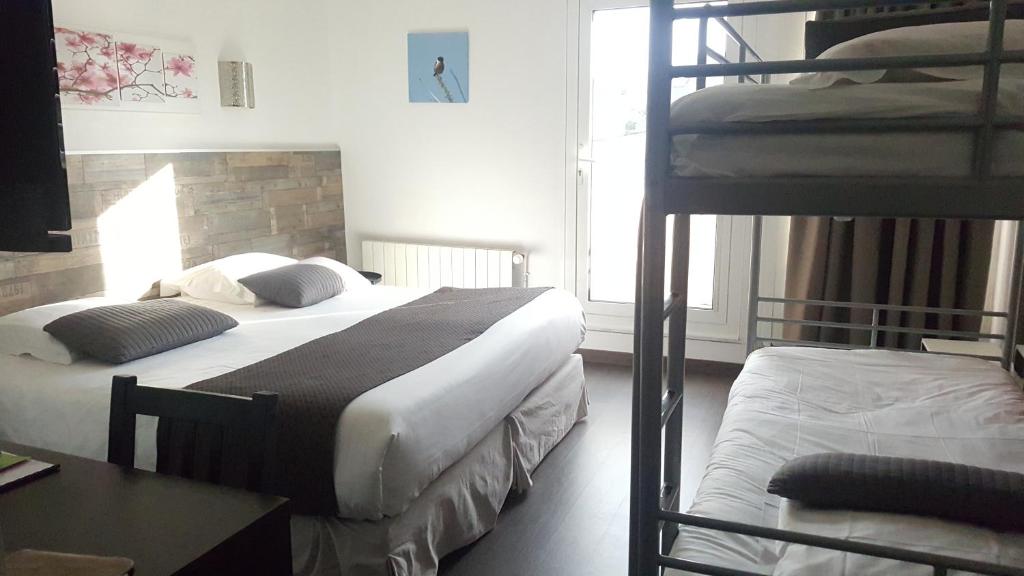 a bedroom with two bunk beds and a desk at Hotel De L'Europe in Perros-Guirec