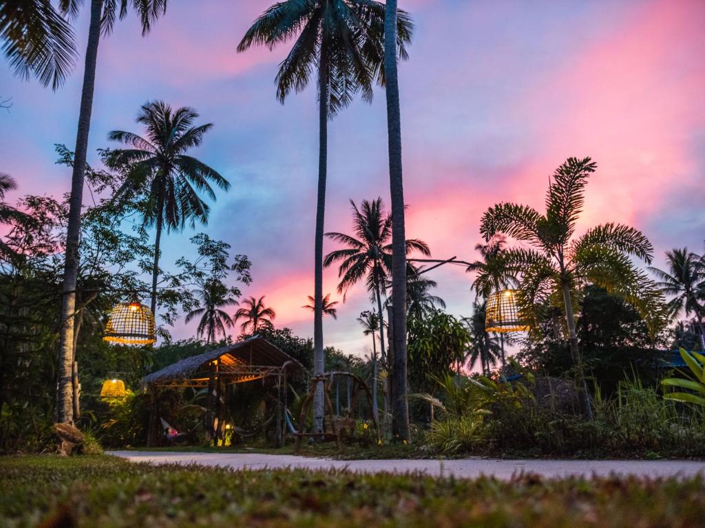 a sunset at a resort with palm trees and a playground at Wonderland Healing Center in Thongsala