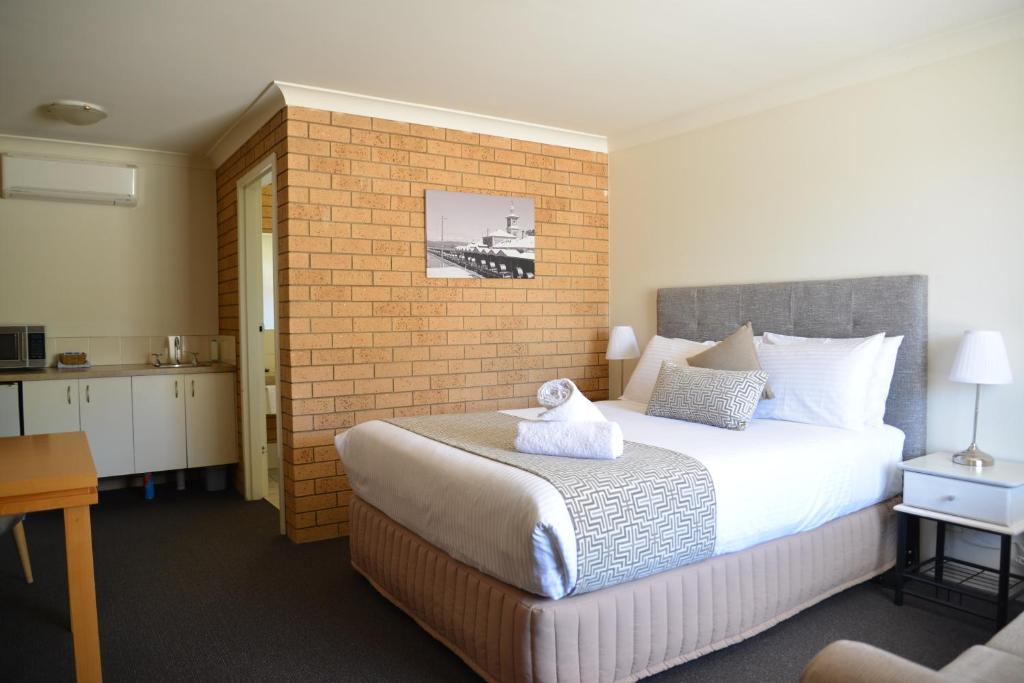 a hotel room with a bed, chair, and nightstand at Albury Allawa Motor Inn in Albury