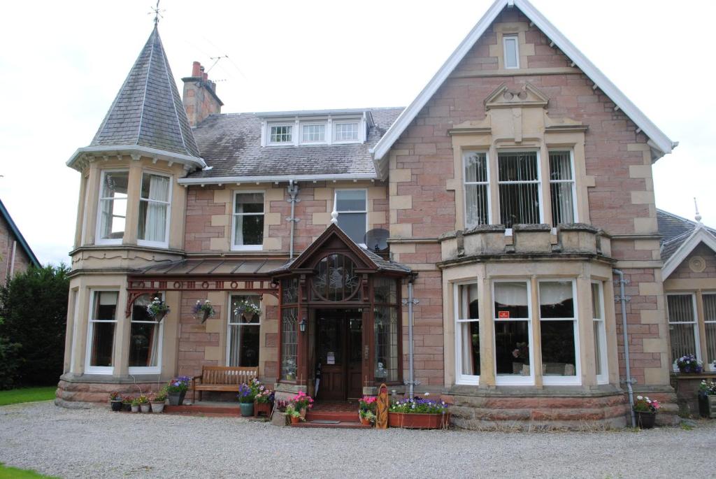 una grande casa in mattoni con un orologio sopra di Chrialdon House a Beauly